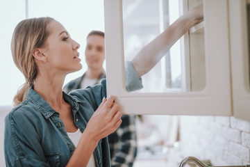 Careful woman putting her hand into the cupboard in her kitchen