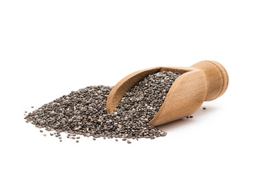 Pile or heap of chia seeds and a small wooden scoop seen from the front and isolated on white...