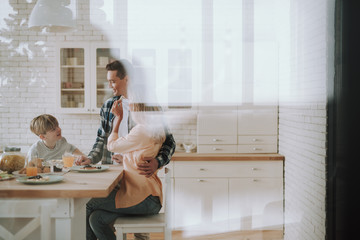Parents kindly looking at their son wheil sitting in the kitchen