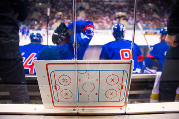 Hockey players sitting on the bench. Tactic board in foreground
