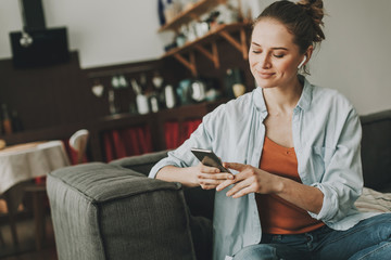 Relaxed lady sitting on sofa with smartphone