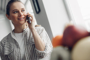 Young female talking by mobile phone at home