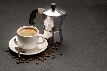 Cup of coffee and a coffee pot on a black concrete background