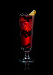 Alcoholic cocktail with black currant on black background