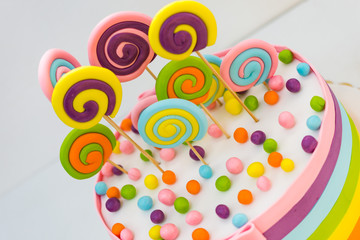 Fototapeta na wymiar Birthday cake with colorful lollipops on a white background