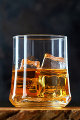 Glass of whiskey with ice cubes (on the rocks) on black background. Copy space