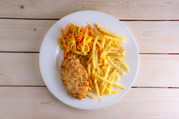 Fried meat in breading with carrot, cabbage, paprika and french fries