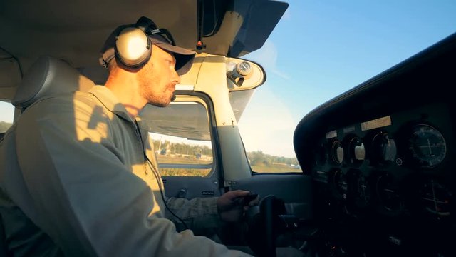 Male aviator pilots a plane in a cockpit, side view.