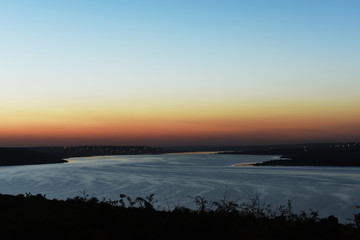 View of the lake in the distance at dusk at sunset. Coast with luminous settlements. Khadzhibeevsky estuary. Ukraine Odessa region.