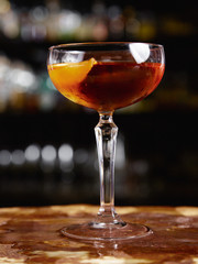 Sweet alcoholic drink in a flat transparent glass in a cozy atmosphere of the bar