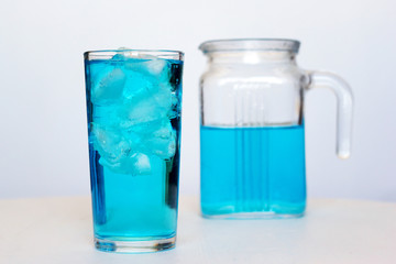 Glass with a blue cocktail with ice on a white background.