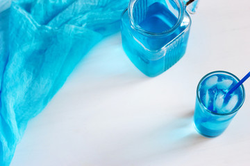Glass with a blue cocktail with ice on a white background. © Elena