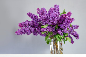 Big bouquet of lilacs from the garden on the table in a glass jar
