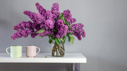 Fototapeta premium Big bouquet of lilacs from the garden on the table in a glass jar