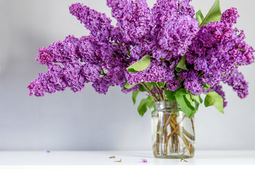 Big bouquet of lilacs from the garden on the table in a glass jar