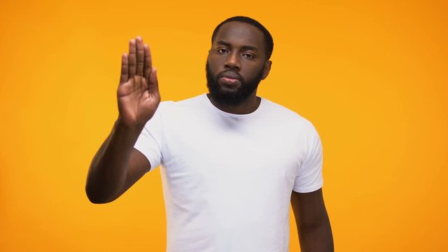 Young black guy showing stop gesture with palm, isolated on yellow background