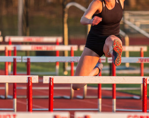 Female runner racing hurdles outdoors