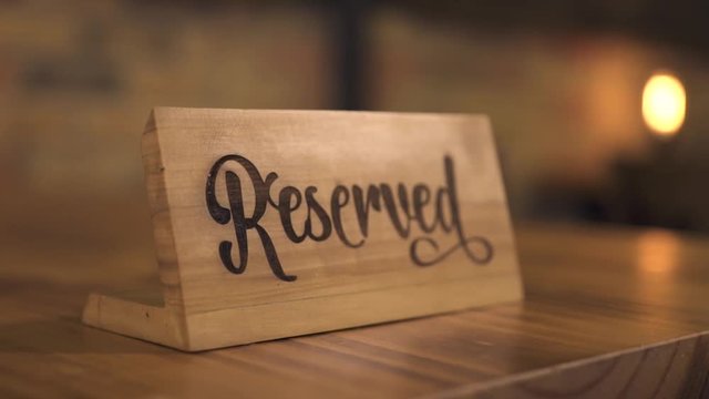 Reserved table sign for reservation seat in elegant restaurant for candle dinner. Wooden reserved table tag in luxury restaurant or cafe for romantic date and dinner with candles.