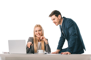 Fototapeta premium blonde businesswoman showing something on laptop to colleague at workplace with cup of coffee