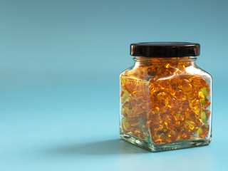 Fish oil capsules in glass bottles on blue background. Healthy omega-3 and stethoscope.