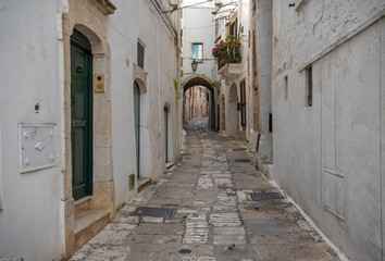 A street view of the old town - province of Brindisi, region of Apulia. Picturesque narrow with traditional white washed houses in the old historic center of Ostuni, Puglia, Italy