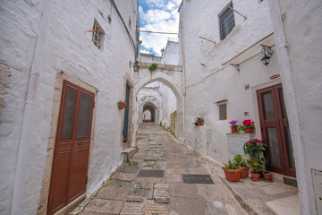 Fototapeta na wymiar A street view of the old town - province of Brindisi, region of Apulia. Picturesque narrow with traditional white washed houses in the old historic center of Ostuni, Puglia, Italy
