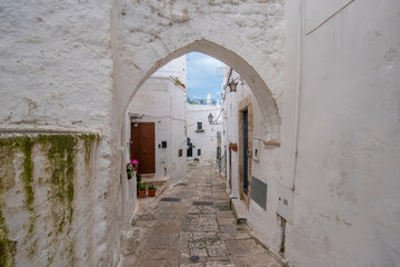 Obraz premium A street view of the old town - province of Brindisi, region of Apulia. Picturesque narrow with traditional white washed houses in the old historic center of Ostuni, Puglia, Italy