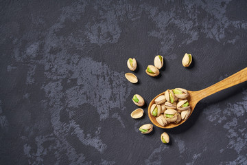 Pistachios  in wooden spoon  on black table ,with copy space ,Top view