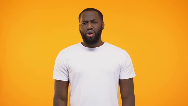 African american man showing confused reaction at camera on yellow background
