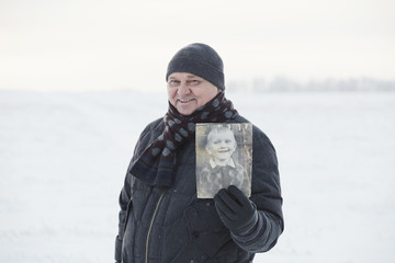 Aged man with his photo as child
