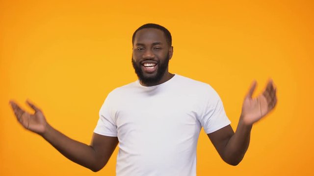 Happy african american man dancing and singing, isolated on yellow background