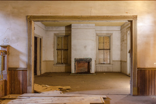 Living room area in old abandoned farmhouse with wainscoting