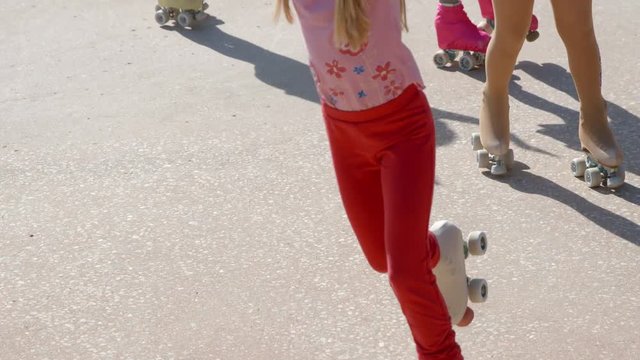 Girls are roller-skating into different directions on the court. They are having fun and are performing a show for the audience.