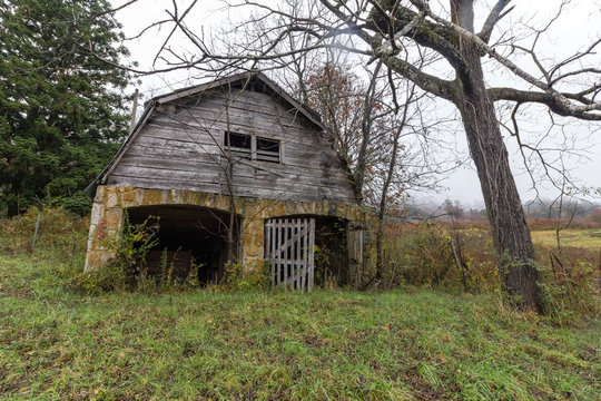 Vintage abandoned barn left to rot in yard of forgotten house