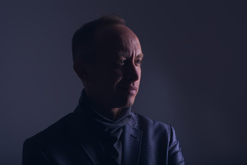 Fototapeta premium Model tests for men. Portrait of an adult male in a low key. Confident look with a smile and a smirk. Blue eyes. Color correction in purple-blue. Stylish image of an adult man