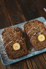 sliced homemade brown cake at blue dish decorated with two banana pieces. vertical.