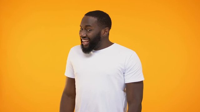 Happy afro american guy smiling and dancing, shrugging and raising brow, flirt