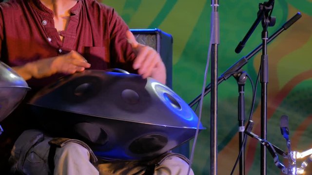 Man playing tank drum or hang on stage of ethnic open air concert. Relaxation, folk, meditative and traditional ethnic music concept