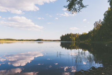 Ausblick auf ruhigen, schwedischen See in dem sich der Himmel spiegelt