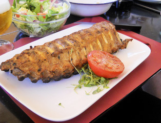 Delicious grilled ribs with tomato and lettuce on white plate