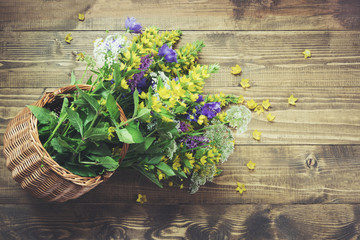 Bouquet of yellow wildflowers in basket on board. Copy space.