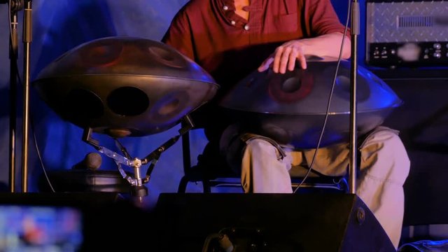 Man playing tank drum or hang on stage of ethnic open air concert. Relaxation, folk, meditative and traditional ethnic music concept