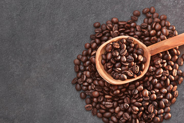 Naklejka premium Coffee beans in a wooden spoon on dark background