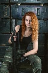 Beautiful girl dressed in military uniform holding a machine gun