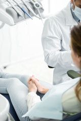 selective focus of woman sitting on chair near dentist