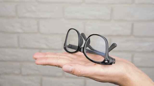 Eyeglasses on the palm. Glasses in black frames on a woman's palm.