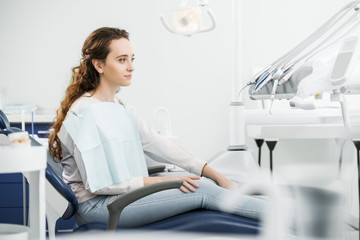 cheerful woman smiling while sitting on chair in dental clinic