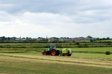 Rural landscapes of Ireland. The tractor works on a meadow.
