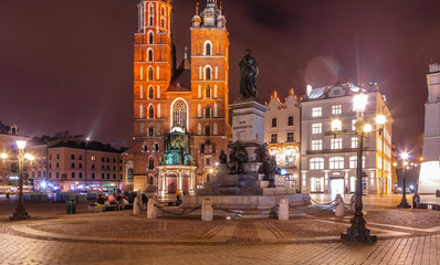 Fototapeta na wymiar Adam Mickiewicz Monument on Main Market Square in front of St. Mary's Basilica in Krakow, Poland at night