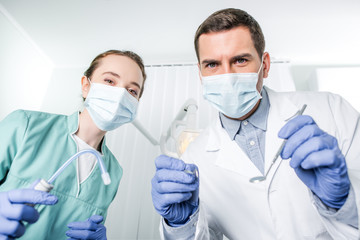 dentists in masks holding dental instruments in hands
